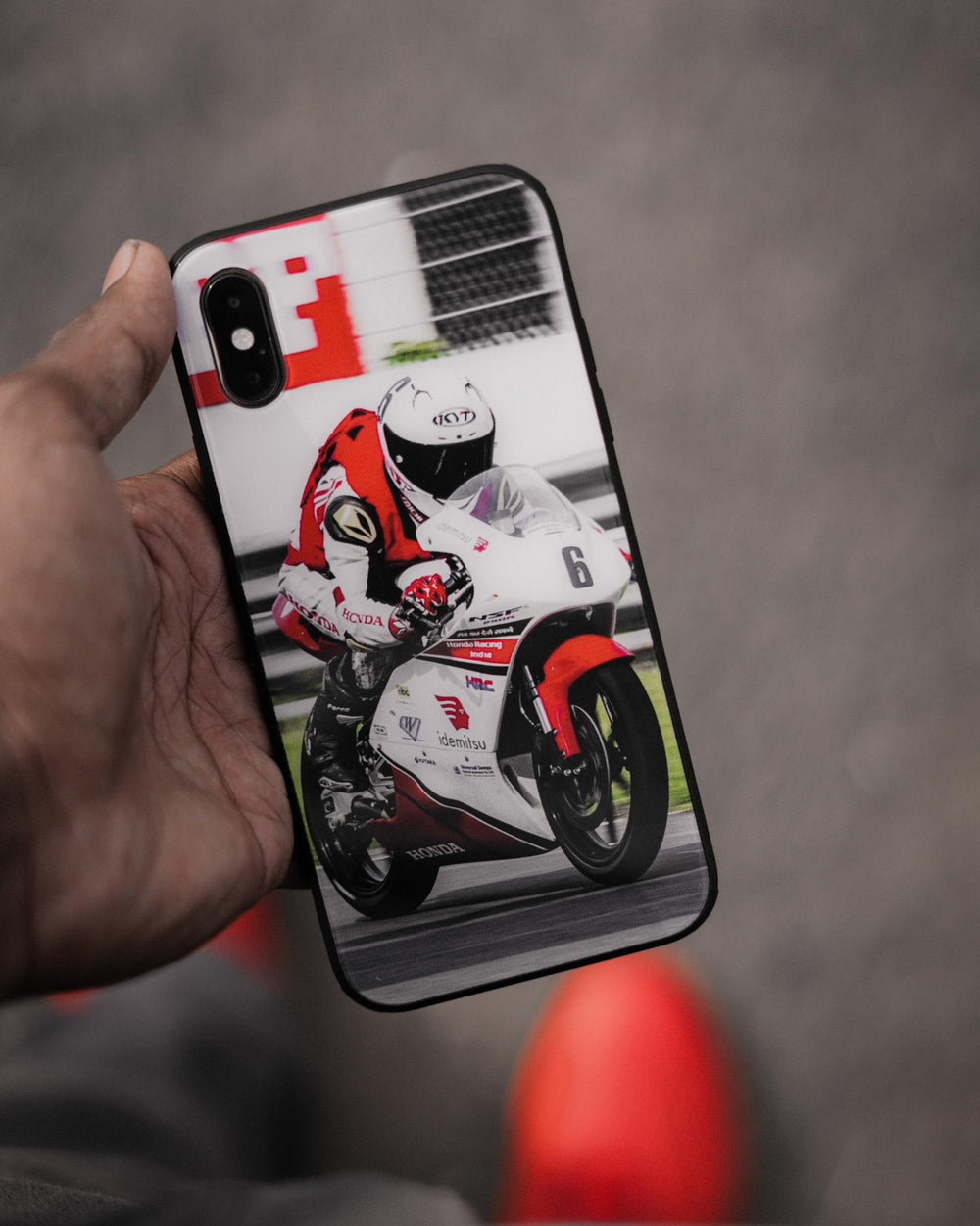 Motorcycle racing print on a black-edged phone case held in hand